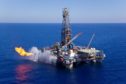 A drilling rig flares gas on a blue sea