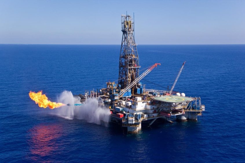 A drilling rig flares gas on a blue sea