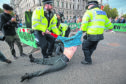 Police remove a demonstrator during an Extinction Rebellion (XR) protest in Westminster, London. PA Photo. Aaron Chown/PA Wire