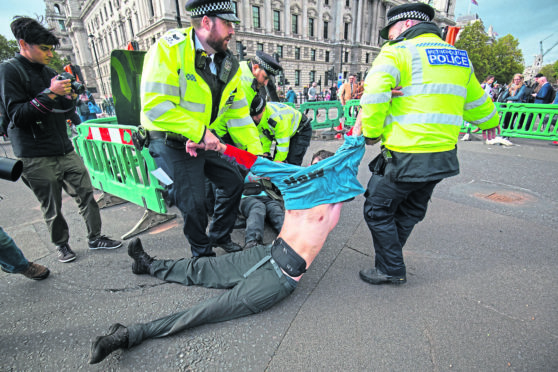 Police remove a demonstrator during an Extinction Rebellion (XR) protest in Westminster, London. PA Photo. Aaron Chown/PA Wire