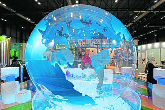 A woman looks at a World globe at the COP25 climate talks congress in Madrid, Spain, Friday, Dec. 13, 2019. (AP Photo/Paul White)