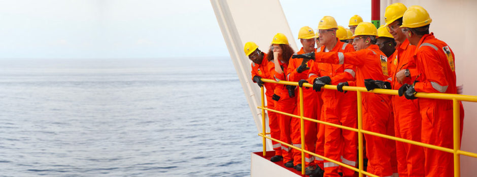 MEn in overalls look out from FPSO into the ocean