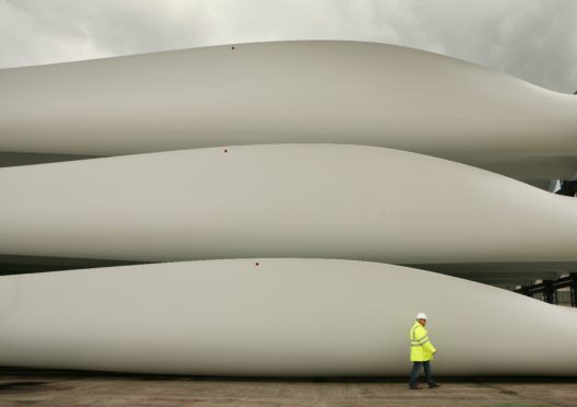 A worker passes stored wind turbine blades at the Harland & Wolff shipyard on August 14, 2008 in Belfast, Northern Ireland. (Photo by Peter Macdiarmid/Getty Images)