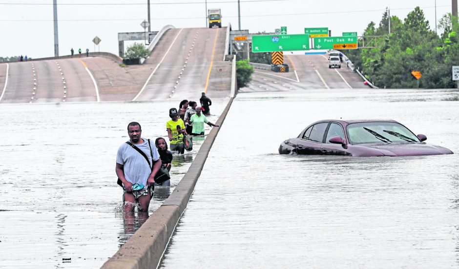 People wade through floodwaters in Houston caused by Tropical Storm Harvey in 2017 (AP Photo/David J. Phillip)