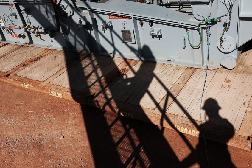 The shadows of workers with Apache Corp. are viewed at the Patterson 298 natural gas fueled drilling rig on land in the Permian Basin on February 5, 2015 in Mentone, Texas.