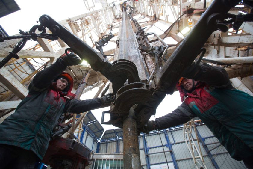 Oil workers connect gear to drilling pipes at the rotary table on a drilling rig, operated by Tatneft PJSC, on an oilfield near Almetyevsk, Tatarstan, Russia, on Tuesday, March 6, 2019. Tatneft explores for, produces, refines, and markets crude oil. Photographer: Andrey Rudakov/Bloomberg