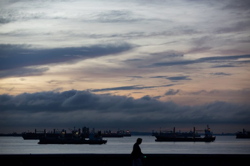 Ships sit moored at sunrise in Singapore.  Photographer: Bloomberg/Bloomberg