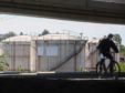 A cyclist wearing a protective face mask rides past oil storage silos at an oil and gas storage facility, operated by Gazprom Neft PJSC, in Belgrade, Serbia, on Tuesday, April 28, 2020. Crude whipsawed near $11 a barrel after a major index tracked by billions of dollars in funds bailed out of near-term contracts for fear prices may turn negative again. Photographer: Oliver Bunic/Bloomberg