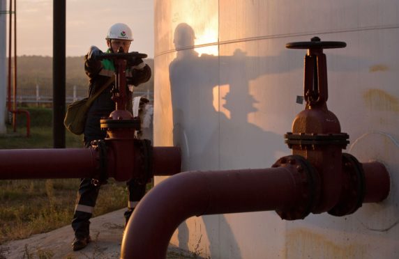 An employee turns a control valve on pipework beside a storage tank at an oil delivery point operated by Bashneft PAO in Sergeevka village, near Ufa, Russia. Photographer: Andrey Rudakov/Bloomberg