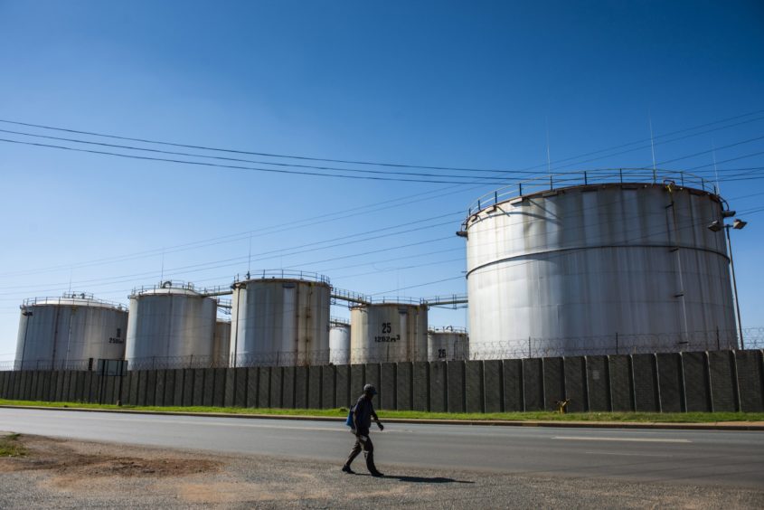 A pedestrian walks alongside oil storage tanks at a facility in the Alrode district