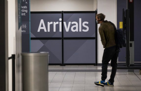 A traveler, wearing a protective face mask, passes through the arrivals area after landing at London Luton Airport in Luton, U.K., on Friday, May 1, 2020. Ryanair Holdings Plc will cut 3,000 jobs and said it will challenge some 30 billion euros ($33 billion) in state aid being doled out to save its European competitors. Photographer: Chris Ratcliffe/Bloomberg