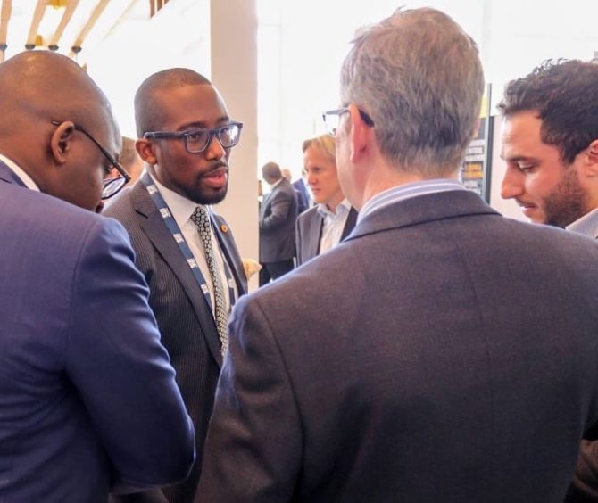 Man in glasses shakes hands with another man in a suit