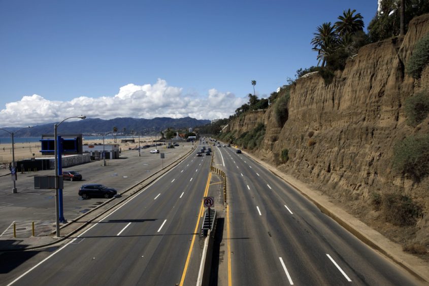 Vehicles drive in light traffic along Pacific Coast Highway north of the Santa Monica Pier, temporarily closed due to the coronavirus, in Santa Monica, California on March 19.
