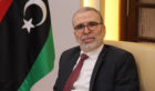 Man with glasses next to part of Libyan flag
