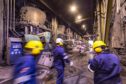 Workers in hard hats in motion through industrial setting