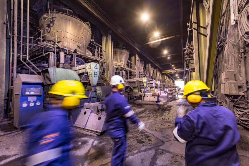 Workers in hard hats in motion through industrial setting