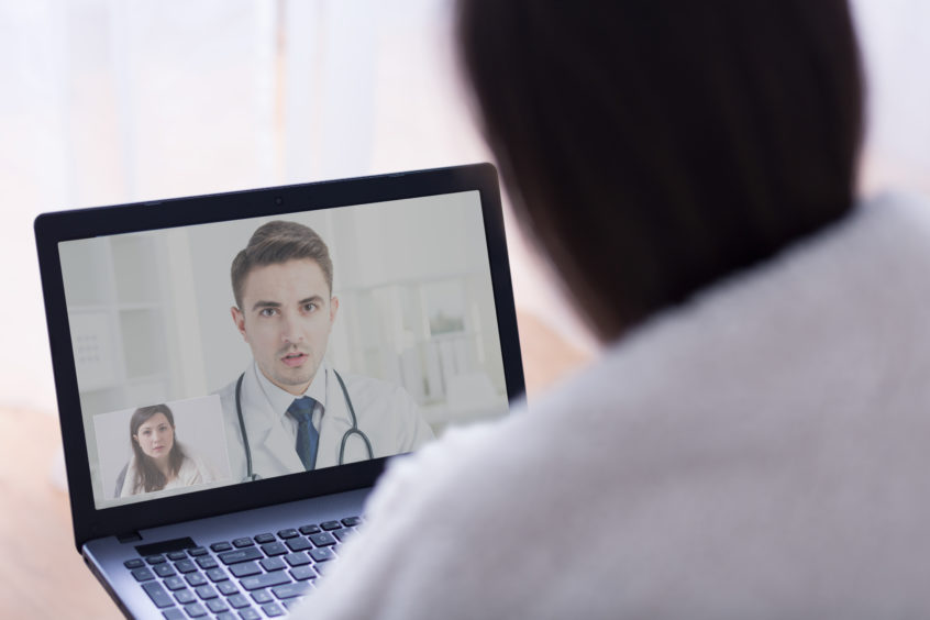 Close-up of a computer screen displaying a video chat between a doctor and a patient