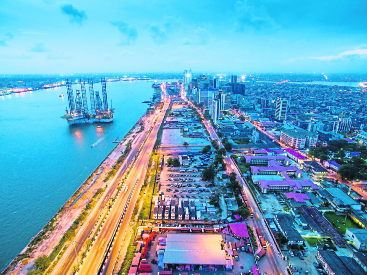 Twilight over a city scene, with a rig on blue water on the left