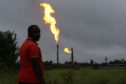 A man looks on as flares burn from pipes at an oil flow station operated by Nigerian Agip Oil Co. Ltd. (NAOC), a division of Eni SpA, in Idu, Rivers State, Nigeria Photographer: George Osodi/Bloomberg