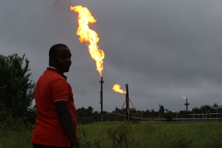 A man looks on as flares burn from pipes at an oil flow station operated by Nigerian Agip Oil Co. Ltd. (NAOC), a division of Eni SpA, in Idu, Rivers State, Nigeria Photographer: George Osodi/Bloomberg