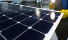 An employee of SunPower Corp. trims the edges and checks solar panels at the SunPower Corp. module manufacturing plant at Flextronics in Milpitas, California, U.S., on Wednesday, Aug. 24, 2011.