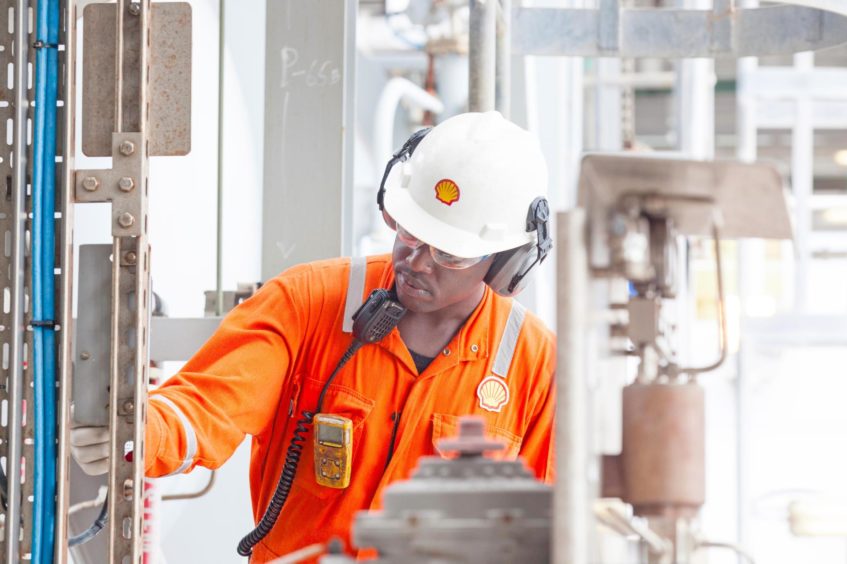 Worker in orange overalls checks equipment on FPSO