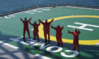 Five workers on a helipad waving