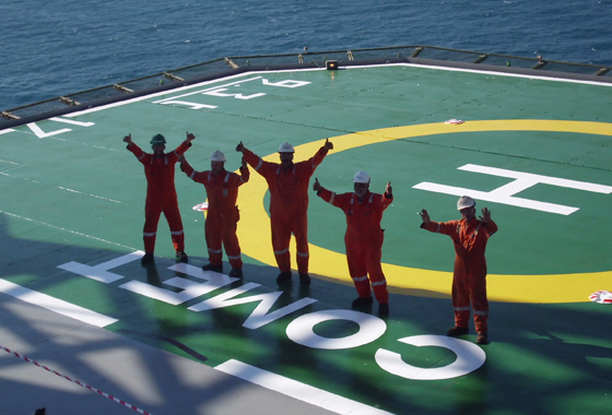 Five workers on a helipad waving