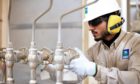 Man in hard hat with gloves gives thumbs up at pipes