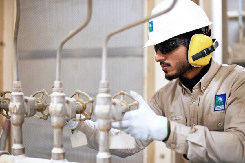 Man in hard hat with gloves gives thumbs up at pipes