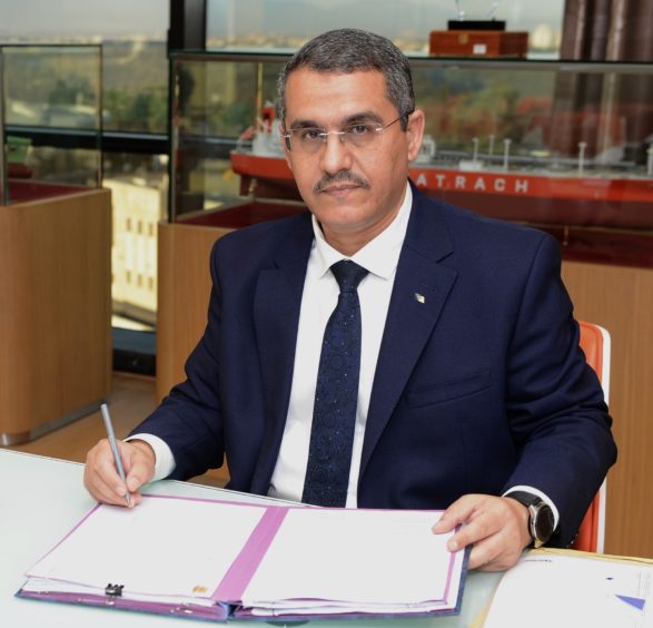 Man with tie signs document while sitting at desk