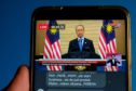 A live news broadcast of Malaysia's Prime Minister Muhyiddin Yassin, is arranged on a smartphone in Shah Alam, Selangor, Malaysia, on Tuesday, Jan. 12, 2021.