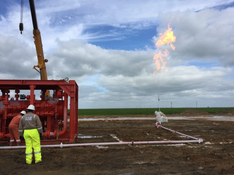 Drilling equipment at work, with a flare in the background