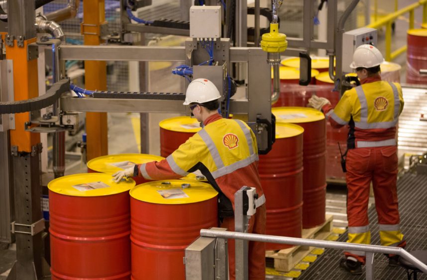 Worker stands at orange oil barrels