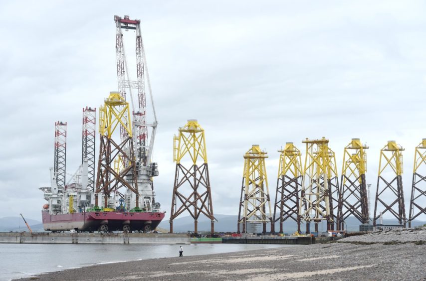 The large floating crane barge, Seajacks Scylla loads wind turbine base platforms at Nigg Energy Park for the Moray East offshore wind farm