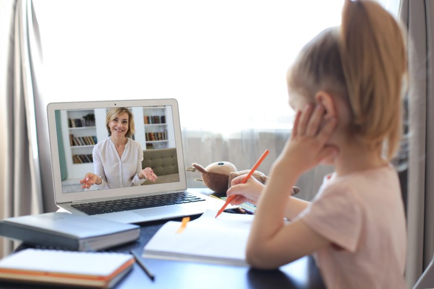 A young girl using laptop computer for an online lesson.