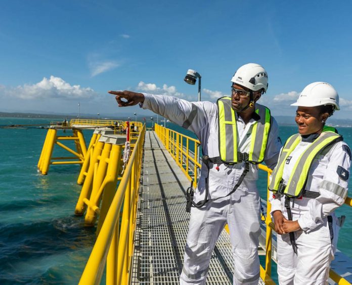 Two men in overalls on a gangway, one points