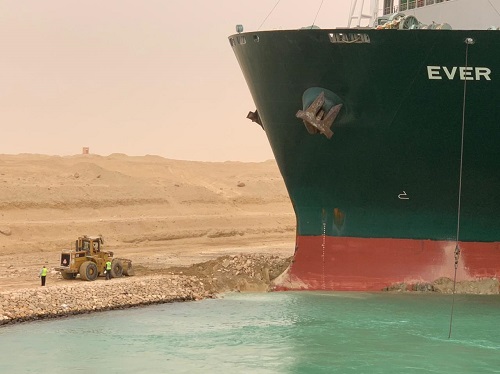 A small digger on the left, the prow of a large cargo ship on the right