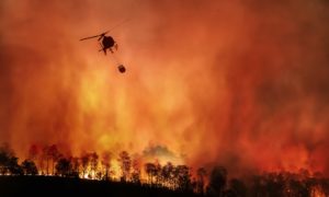 Fire fighting helicopter carry water bucket to extinguish forest fire in Indonesia: fire fighters have also been battling a blaze at the Cilacap oil refinery