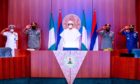 Uniformed officers salute at Nigerian podium.