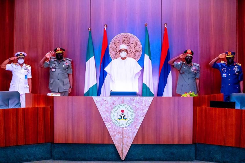 Uniformed officers salute at Nigerian podium.