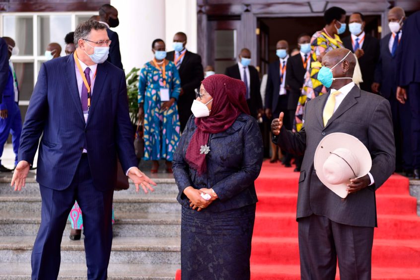 Two men and a woman stand in front of a red carpet