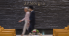 Two blurry people walk in front of wall saying JP Morgan
