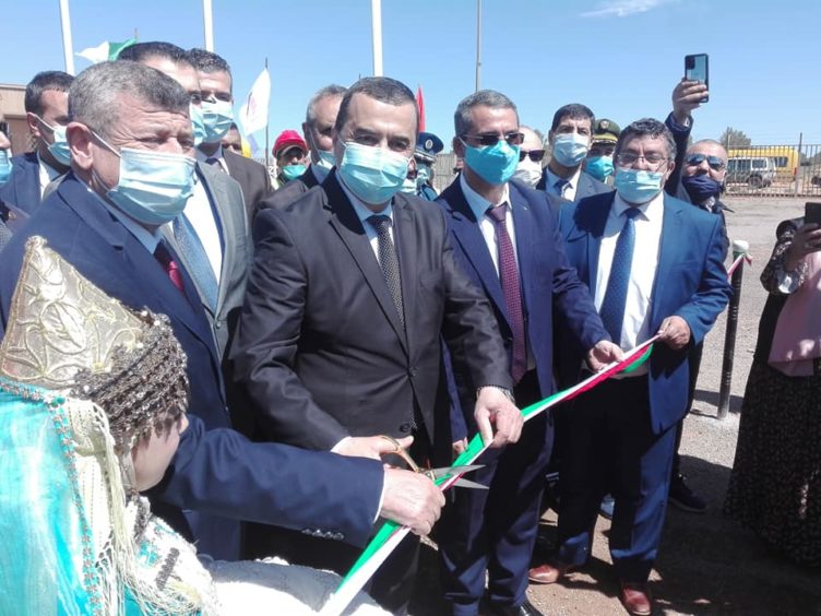 Group of men in suits, one cutting a ribbon,