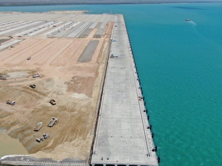 An aerial shot of a port on the left hand side with the ocean on the right