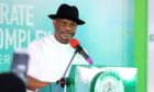 Governor Wike talks at a podium, with a green background