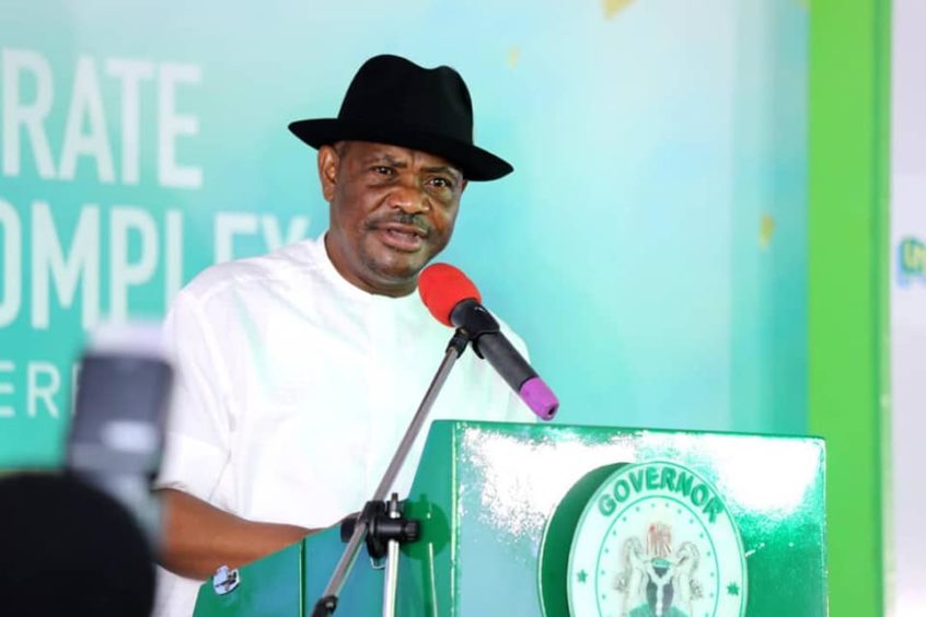 Governor Wike talks at a podium, with a green background