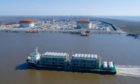 A ship carrying LNG equipment moves along a waterway