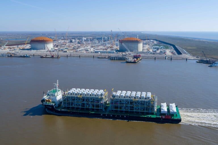 A ship carrying LNG equipment moves along a waterway