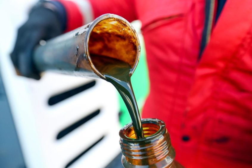 An employee pours a sample of oil from a bottle into a measuring vessel at a drilling site. Photographer: Bloomberg Creative Photos/Bloomberg